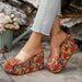 Colorful woven platform shoes worn with light blue jeans against a stone wall background.