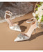 White wedding shoes with embellishments on a beige surface with floral decorations.