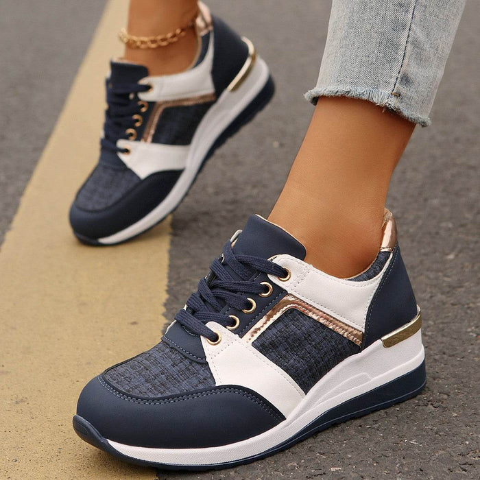 Navy and white sneakers with gold accents worn on a pavement background