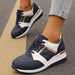 Navy and white sneakers with gold accents worn on a pavement background