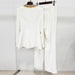White outfit with gold embellishments on a hanger against a white background