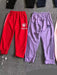 Red and purple tracksuits with brand logos on a gray surface