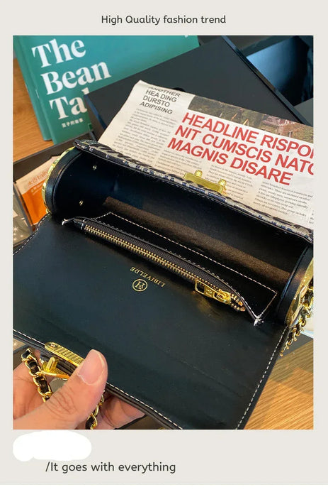 Black leather wallet with gold accents held open to show interior, on a desk with books and newspaper.