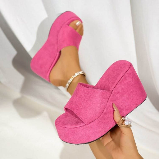 Pink platform sandals being worn on a white background
