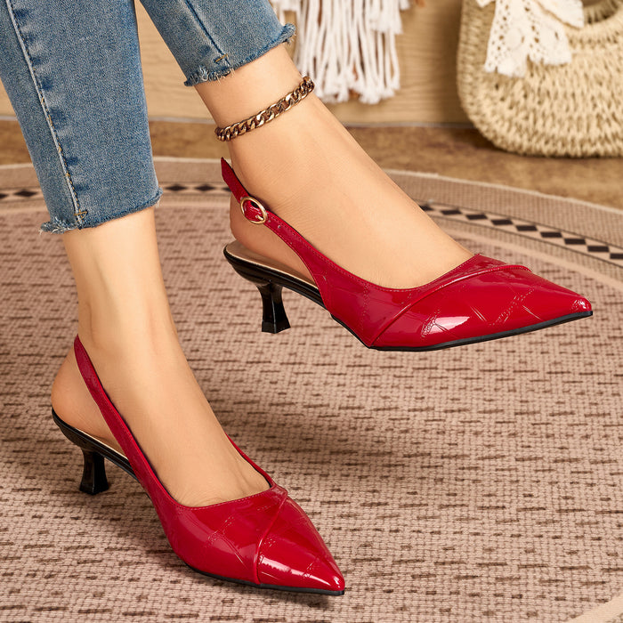 A pair of red patent leather slingback pumps with kitten heels, shown on a model wearing blue jeans. The shoes feature a pointed toe and a small gold-tone buckle at the back of the slingback strap.