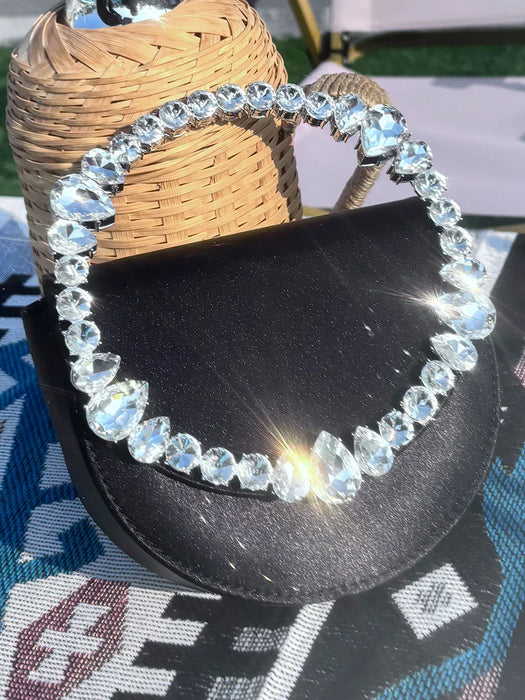 Black sandal with crystal embellishments on a textured surface