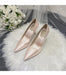 Pair of pink high-heeled shoes on a white fur surface with a bouquet of white roses in the background.
