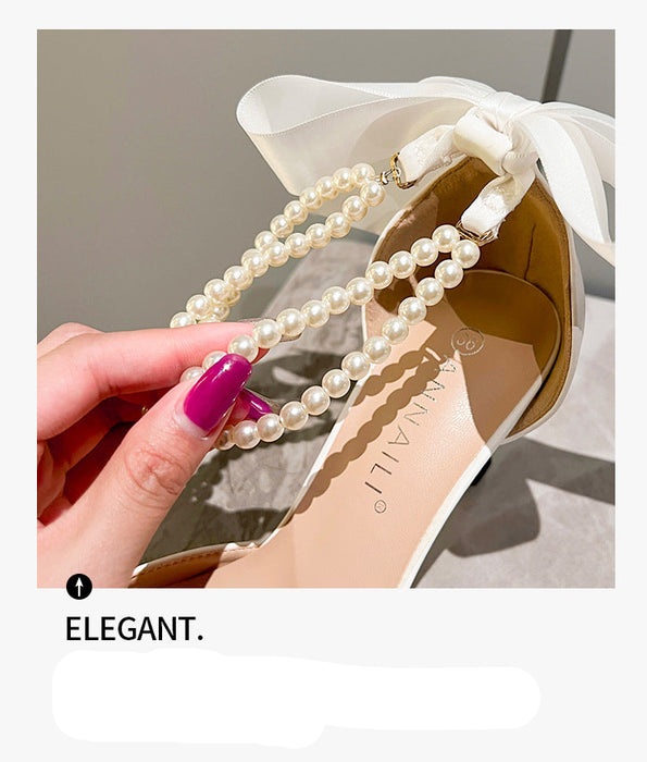 Pearl strap on a shoe with a hand holding it, set against a neutral background.