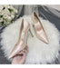 Pair of pink high-heeled shoes on a white fur surface with a bouquet of white flowers in the background.