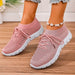 Pink sneakers with white soles worn on a wooden floor.