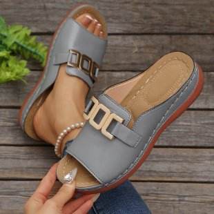 Gray sandals with gold accents on a wooden surface