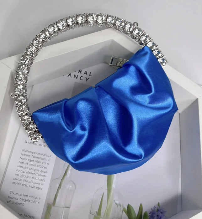 Blue satin headband with crystal embellishments on a white surface