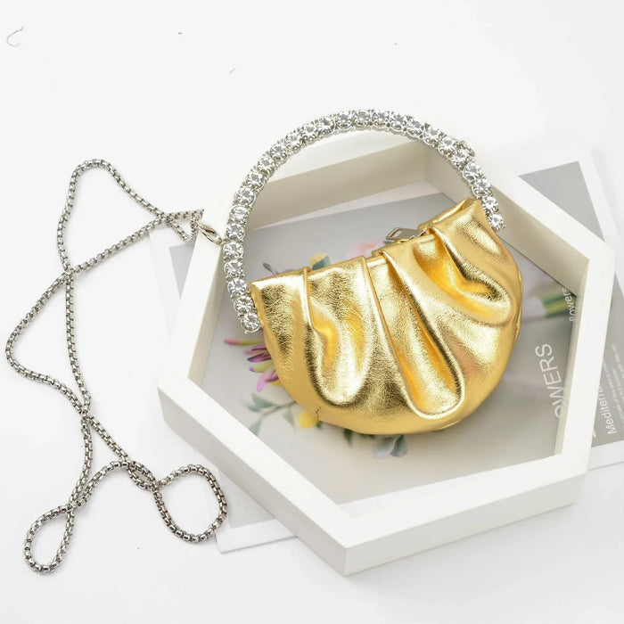 Gold handbag with a chain strap on a white surface