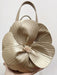 Beige handbag shaped like a flower with a pearl center held by a hand against a light background