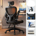 Black office chair in a room with a computer setup, featuring adjustable features on the right.