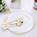 Gold cutlery set on a decorative white plate with a blurred background