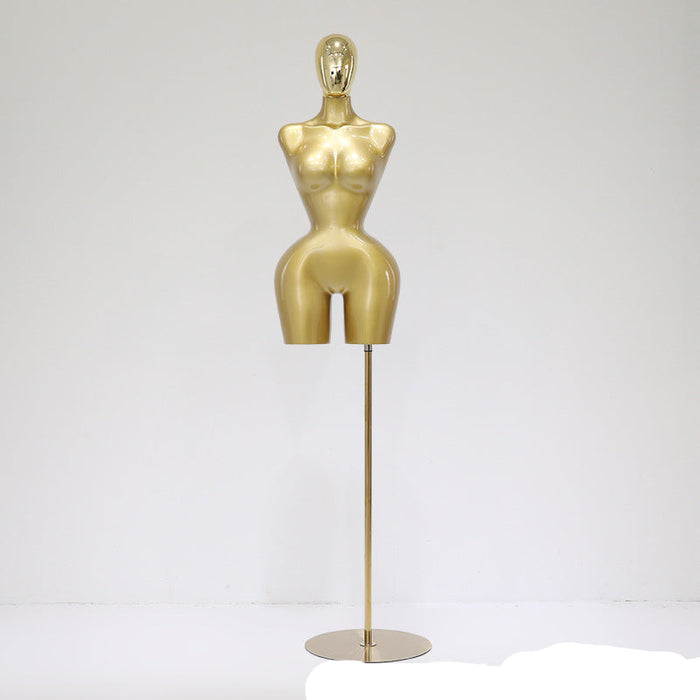 Gold mannequin on a stand against a white background