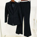 Black suit jacket and pants on hangers against a white background