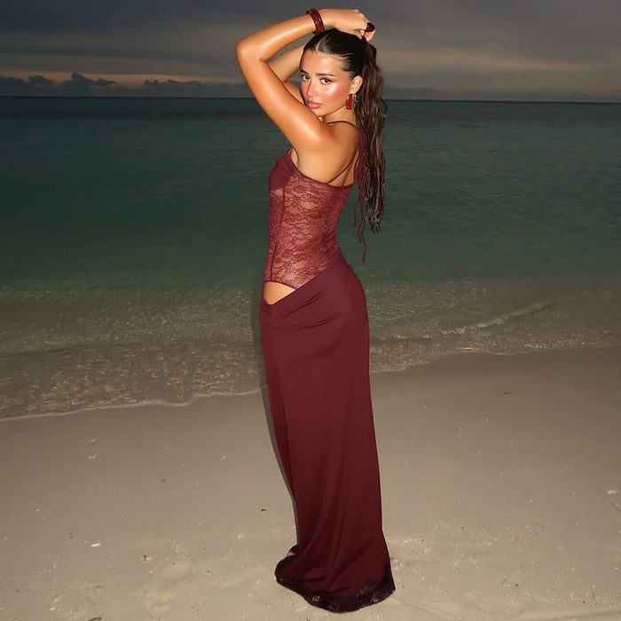 Woman in a burgundy dress standing on a beach at sunset.