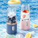 Two portable blenders with ingredients on a poolside table.