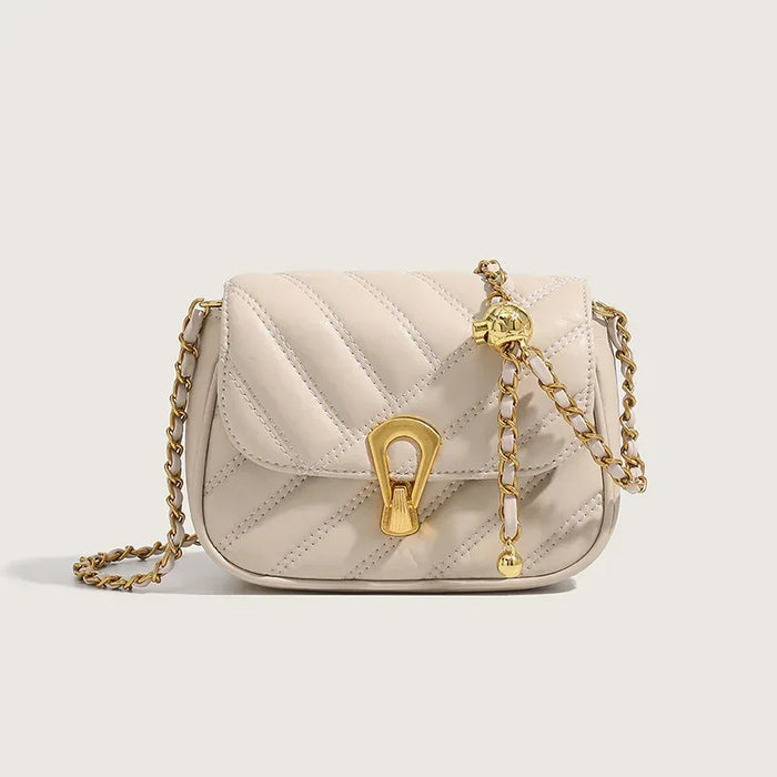 Quilted cream handbag with gold chain strap on a light beige background
