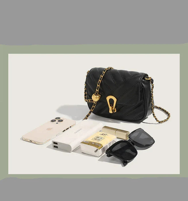 Black handbag with gold chain on a light gray background