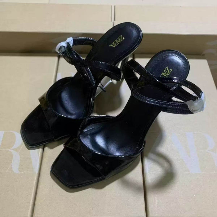 Black high-heeled sandals with 'Zara' branding on a beige surface.