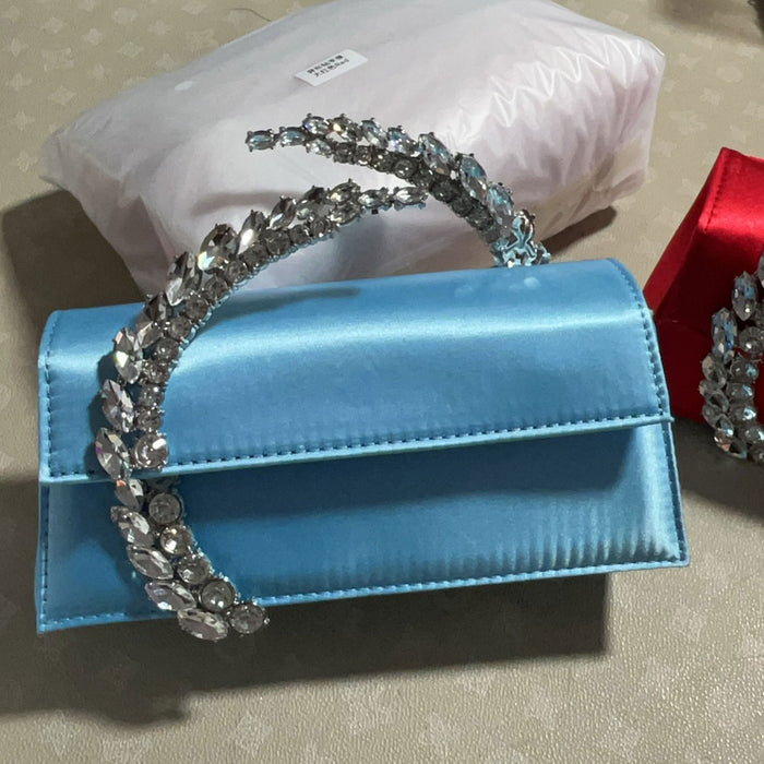 Blue handbag with decorative silver handle on a neutral background