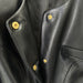 Close-up of a black leather jacket with gold buttons