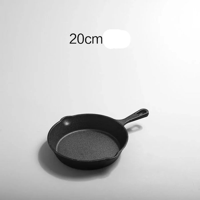 Black cast iron skillet with '20cm 煎锅' text on a light gray background