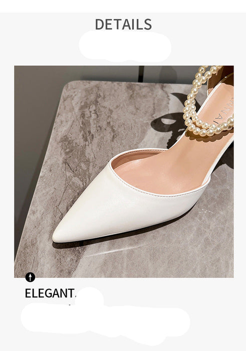 White high-heeled shoe with pearl necklace on a gray surface