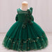 Green children's dress with floral details on a mannequin against a plain background