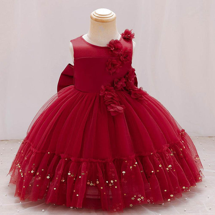 Red children's dress with floral details on a mannequin against a white background