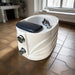 White pedicure chair with black cushion on a tiled floor in a spa-like setting.
