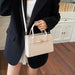 A person wearing a black blazer and white pleated skirt carries a structured cream-colored crocodile-embossed handbag with gold hardware and a white shoulder strap in an indoor setting with wooden floors and white cabinets.
