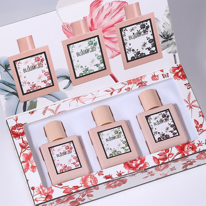Set of four perfume bottles with floral designs in a decorative box.