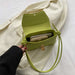 Green handbag held by a hand on a white background