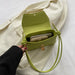 Green handbag held by a hand on a white background