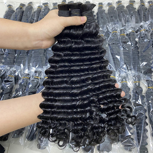 Person holding a bundle of black hair extensions with packages in the background