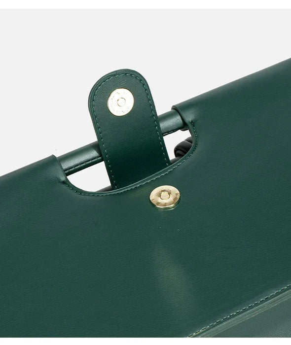 Close-up of a green handbag with gold hardware on a white background