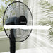 Black solar fan on a white surface with greenery in the background