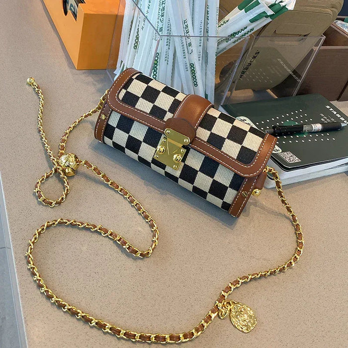 Checkered handbag with gold chain on a desk