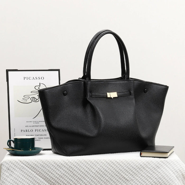 Black handbag on a white surface with a book and cup in the background