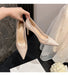Beige high-heeled shoes being held with a blurred background