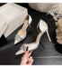 White high-heeled shoes with embellishments on a dark surface next to a white box.