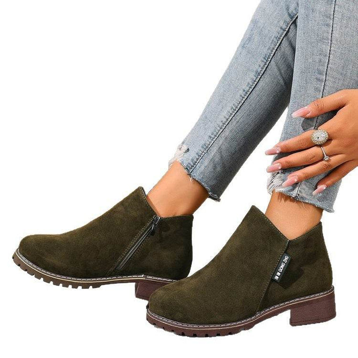 Green suede ankle boots worn with light blue jeans on a white background