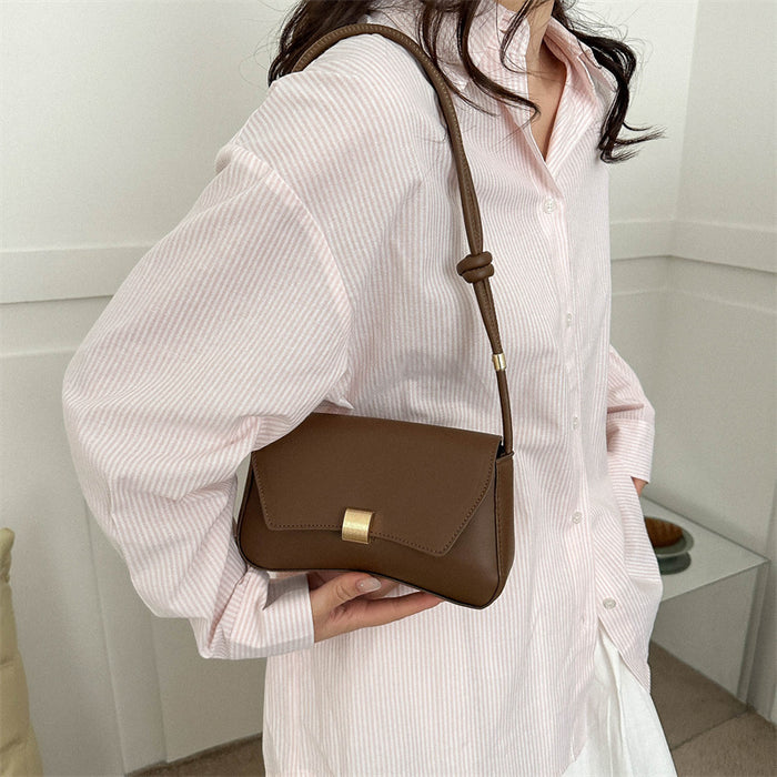 Person holding a brown leather handbag with a white background