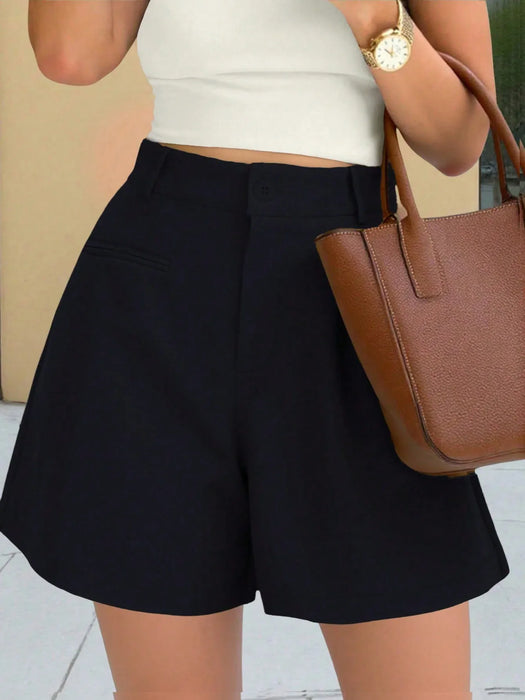 Person wearing black shorts with a white top and brown handbag.