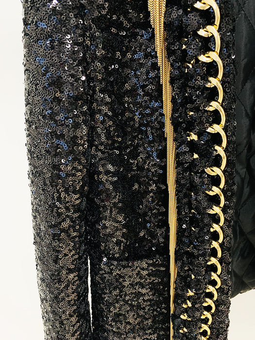 Black sequined outfit with gold zipper and decorative trim on a white background