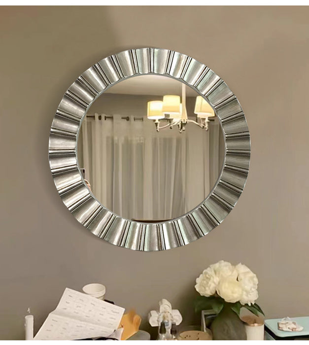Round decorative mirror with a metallic frame on a wall.